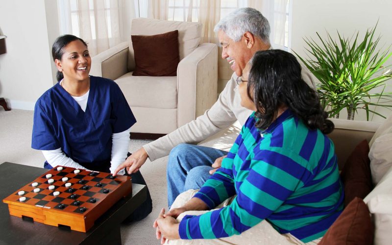 Home health care worker and an elderly couple playing game